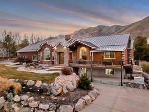 View of front facade featuring brick siding, a chimney, a standing seam roof, and a mountain view