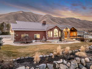 View of front of property featuring brick siding, a chimney, a front lawn, and a mountain view
