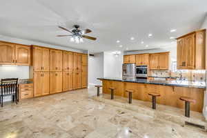 Kitchen featuring a breakfast bar area, a peninsula, dark stone countertops, and recessed lighting