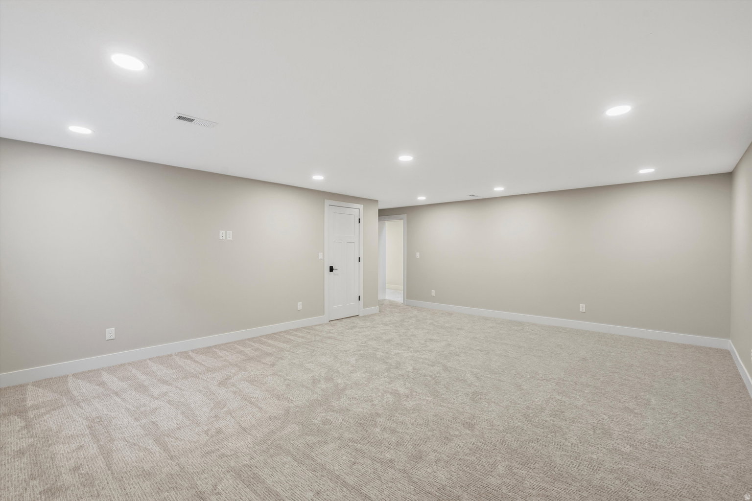 Finished below grade area featuring recessed lighting and light carpet