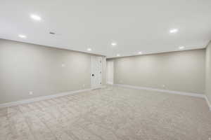 Finished below grade area featuring recessed lighting and light carpet