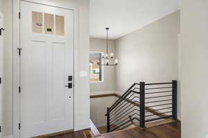 Foyer entrance with dark wood-style floors and hanging lights