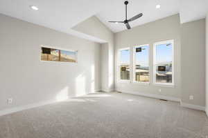 Carpeted empty room with ceiling fan, lofted ceiling, and recessed lighting
