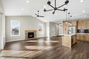 Kitchen with open floor plan, a kitchen island with sink, a fireplace, decorative light fixtures, and decorative backsplash