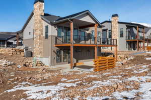 Back of property with a patio, a chimney, board and batten siding, and a wooden deck