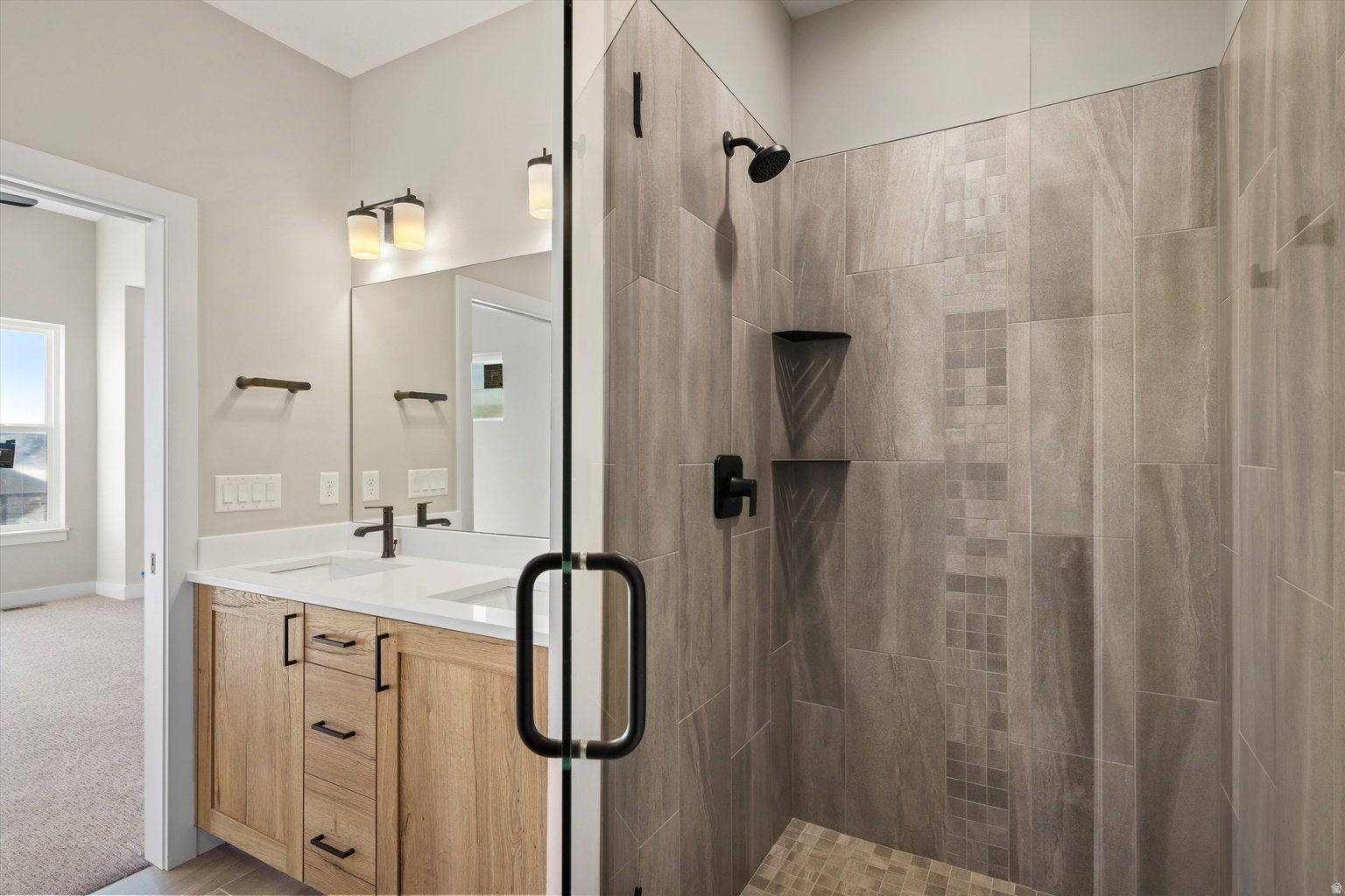 Full bathroom with double vanity, a shower stall, and light colored carpet