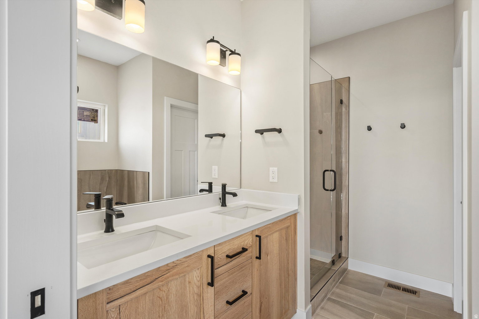 Bathroom featuring double vanity, a shower stall, and wood finish floors