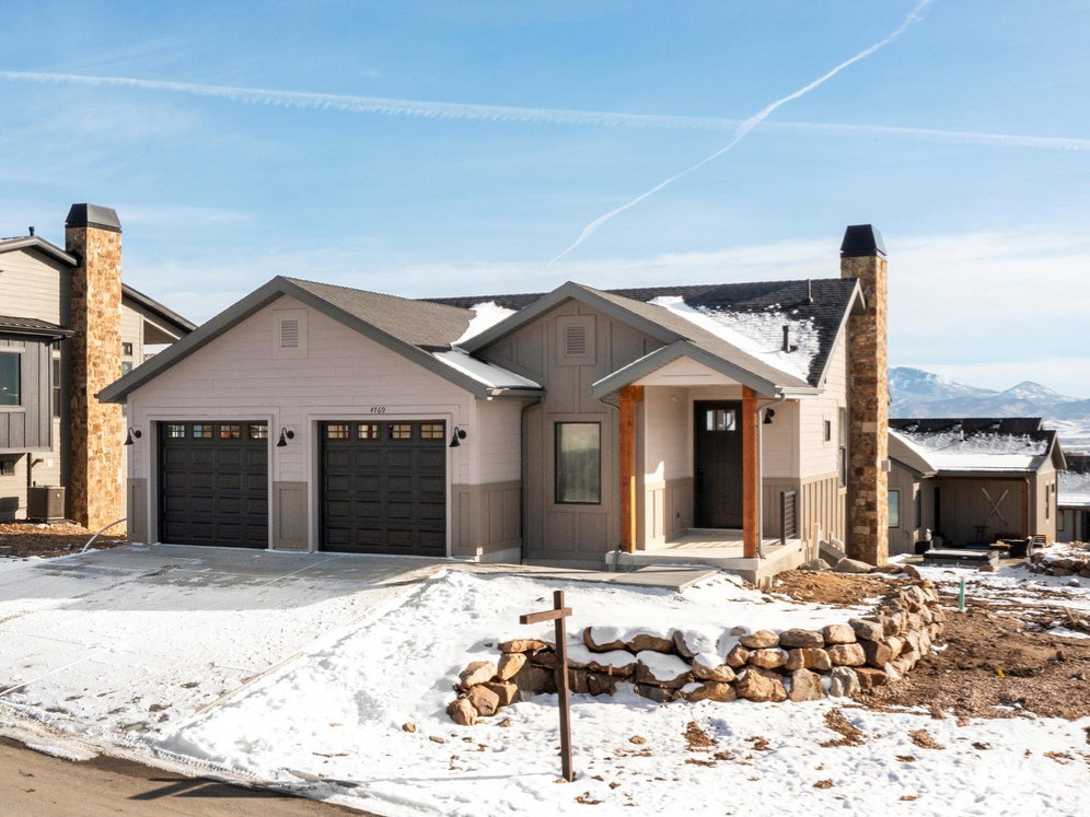 Modern farmhouse featuring a chimney, concrete driveway, and an attached garage