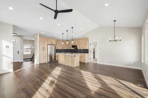 Kitchen with hanging lights, open floor plan, a center island with sink, a ceiling fan, and high quality fridge