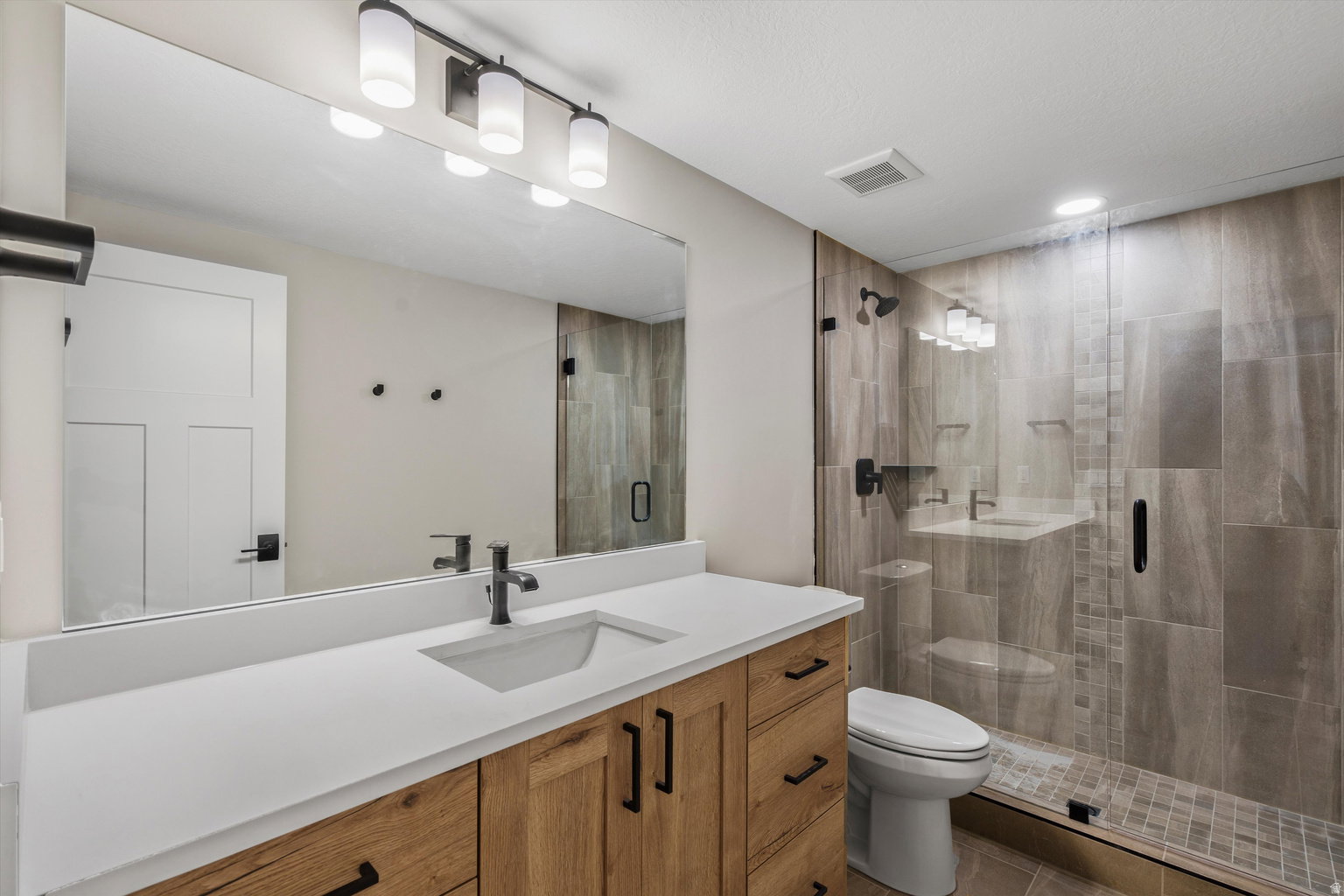 Full bath with a shower stall and vanity