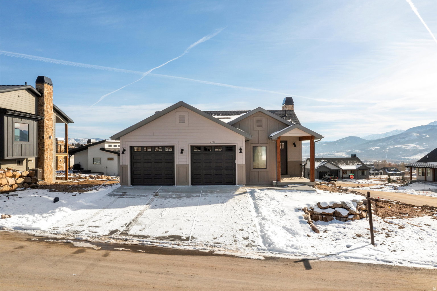View of front of house featuring board and batten siding, a chimney, an attached garage, and a mountain view