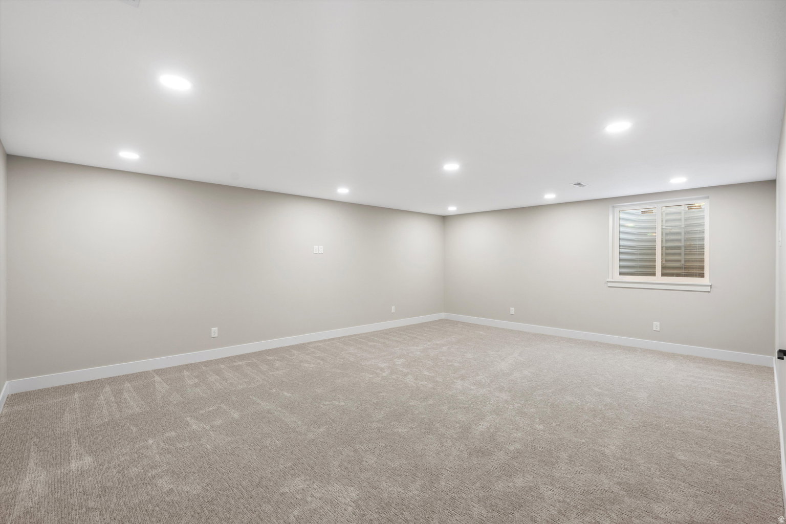 Finished below grade area featuring light carpet and recessed lighting