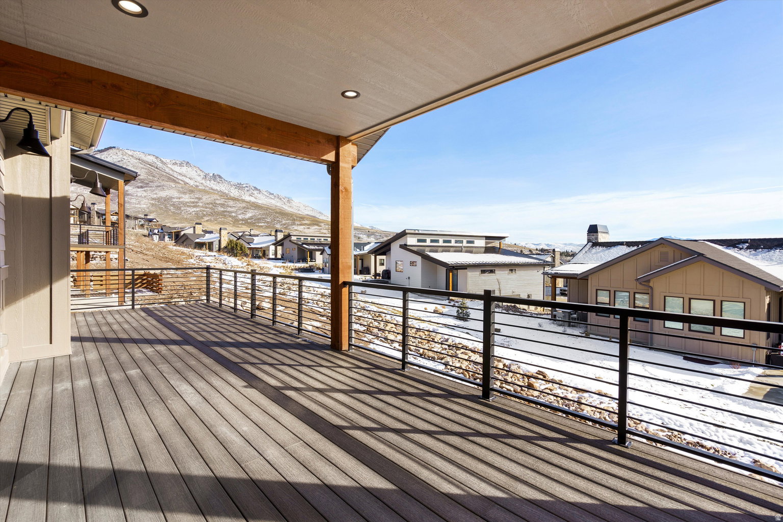 Snow covered deck featuring a residential view and a mountain view
