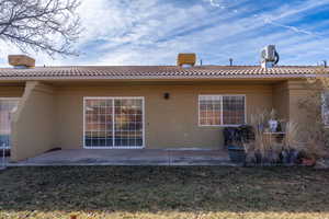 Rear view of property featuring a patio, stucco siding, a lawn, and a tiled roof