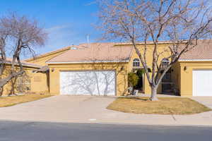 View of front facade with stucco siding, an attached garage, a tile roof, and a gate