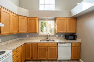 Kitchen featuring white appliances, light stone countertops, and wood finish cabinets
