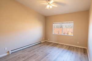 Empty room featuring baseboard heating, a ceiling fan, and light wood-style flooring