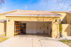 Rear view of house featuring a garage, stucco siding, concrete driveway, and a tiled roof