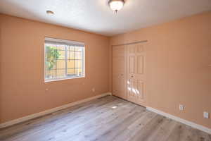 Unfurnished bedroom featuring light wood finished floors and a closet