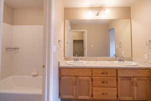 Full bathroom with double vanity and shower / bath combination