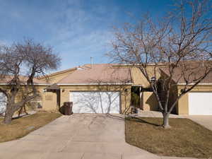 View of front facade featuring a gate, concrete driveway, stucco siding, and an attached garage