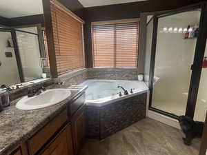 Full bath with a stall shower, vanity, and a whirlpool tub