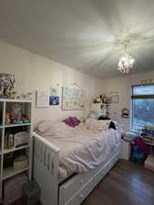 Bedroom with dark wood-style floors and a chandelier