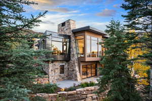 Back of house with a chimney and stone siding