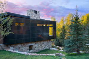 Property exterior at dusk featuring stone siding and a lawn