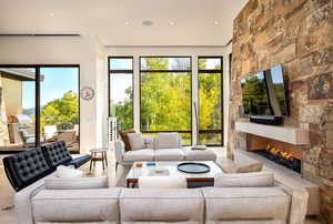 Living room with a stone fireplace, healthy amount of natural light, recessed lighting, and wood finished floors