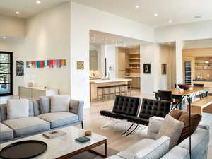 Living room with light wood finished floors, recessed lighting, a high ceiling, and beverage cooler