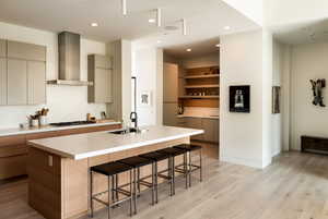 Kitchen with a kitchen breakfast bar, light wood finished floors, gray cabinets, modern cabinets, and recessed lighting