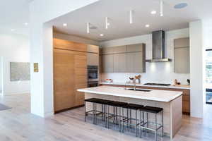 Kitchen with a kitchen breakfast bar, modern cabinets, a kitchen island with sink, light wood-style floors, and recessed lighting