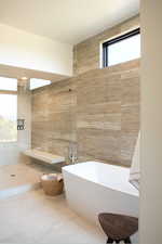 Bathroom featuring tile walls, tiled shower, and a soaking tub