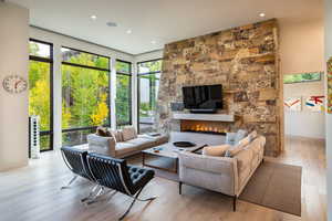 Living room with a stone fireplace and wood-type flooring