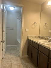 Bathroom featuring vanity, washtub / shower combination, and light tile patterned floors