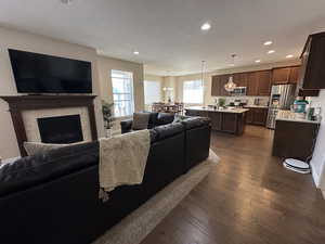 Living room featuring dark wood-style flooring, a textured ceiling, a fireplace, and recessed lighting
