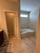 Full bathroom with a garden tub, vanity, and a textured ceiling
