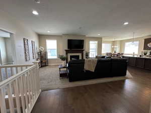 Living area with dark wood-style floors, a fireplace, recessed lighting, and a textured ceiling