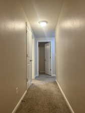 Hall featuring light colored carpet and baseboards
