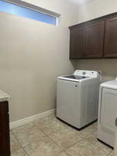 Laundry area with cabinet space, washer and clothes dryer, and light tile patterned flooring