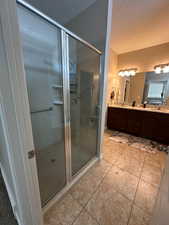 Bathroom featuring double vanity, a shower stall, a textured ceiling, and light tile patterned floors