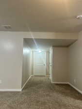 Corridor featuring a textured ceiling and carpet floors