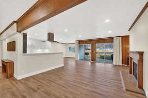 Unfurnished living room with ornamental molding, recessed lighting, light wood-type flooring, and a fireplace with raised hearth
