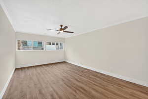 Empty room with light wood-style flooring, crown molding, and a ceiling fan