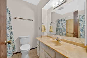 Full bathroom with vanity, curtained shower, and light tile patterned flooring
