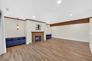Unfurnished living room featuring a fireplace, light wood-type flooring, recessed lighting, and ornamental molding