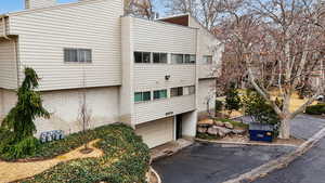 View of home's exterior featuring an attached garage, asphalt driveway, brick siding, and a chimney