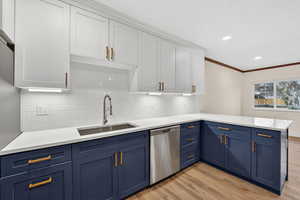 Dual tone kitchen featuring a peninsula, dishwasher, two tone cabinets, light wood-style flooring, and ornamental molding