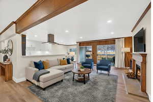Living area featuring ornamental molding, light wood finished floors, recessed lighting, and a warm lit fireplace